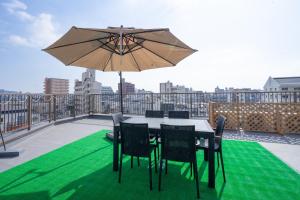 a table and chairs on a balcony with an umbrella at cozy 3rd stay in Okayama