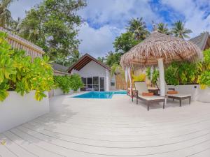 a patio with chairs and an umbrella and a swimming pool at Malahini Kuda Bandos Special Offer Begin your island escape with ease airport pick up and return by shared speedboat at just USD 50 per person stays stay untill end October 2026 in North Male Atoll