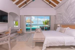a bedroom with a bed and a view of the ocean at Malahini Kuda Bandos Special Offer Begin your island escape with ease airport pick up and return by shared speedboat at just USD 50 per person stays stay untill end October 2026 in North Male Atoll