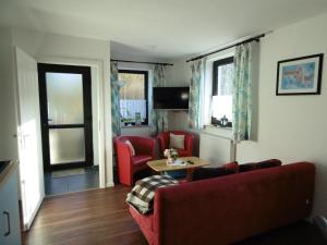 a living room with a red couch and a table at Ferienwohnung Schäfer in Waldbreitbach