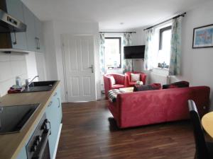a living room with a red couch and two chairs at Ferienwohnung Schäfer in Waldbreitbach +16 photos