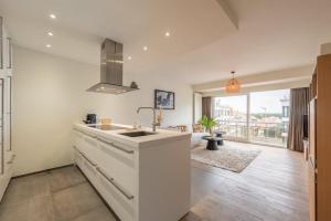 a white kitchen with a sink and a large window at Modern Cozy Studio - Prime location Knokke in Knokke-Heist