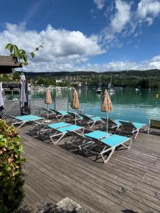 a group of lounge chairs and umbrellas on a dock at Strandhaus am Wörthersee in Velden am Wörthersee