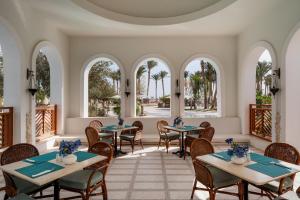 a dining room with tables and chairs and windows at Grand Makadi - Couples and Families Only in Hurghada
