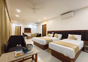 a hotel room with two beds and a living room at Hotel Vamshi Grand in Lingampalli