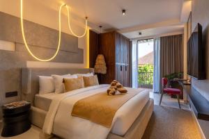 a bedroom with a large bed with a teddy bear on it at Palermo Suites by DH in Ubud
