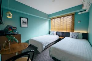 a room with two beds and a desk and a table at Hotel She, Kyoto in Kyoto
