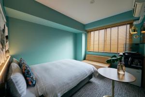 a bedroom with a bed and a table and a window at Hotel She, Kyoto in Kyoto