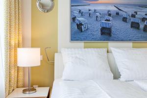 a bedroom with a bed and a picture of a beach at Golfresidenz B 002 in Grömitz +24 photos