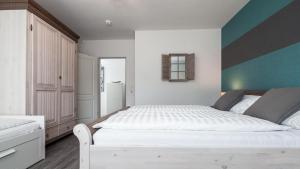 a bedroom with a white bed with a blue accent wall at Golfresidenz B 105 in Grömitz +24 photos