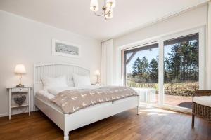 a white bedroom with a bed and a large window at Golfresidenz B 010 Heimathafen in Grömitz +29 photos