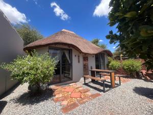 a small hut with a thatched roof and a bench at Martinique Guesthouse in Kathu