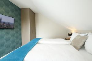 a bedroom with a white bed with a tv on the wall at Amelie No 3 Hotel & Appartements in Schweigen-Rechtenbach