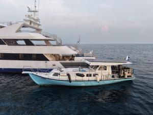 a boat in the water next to a cruise ship at RITRELLA FLOATING HOTEL&YACHT - FREE beach access daily - Full board meal plan in Male City