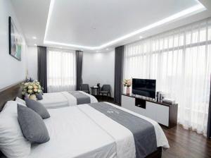 ein Hotelzimmer mit zwei Betten und einem Flachbildfernseher in der Unterkunft Realux Hotel FLC Sam Son in Sầm Sơn