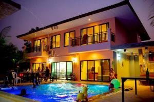 a group of people playing in a swimming pool in front of a house at Baanphet Sukphrom Wang Nam Khiao in Ban Khlong Ta Sang