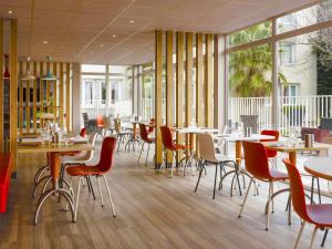 a restaurant with tables and chairs and windows at ibis Arles in Arles