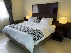 a bedroom with a large bed with white sheets and pillows at Axari Hotel & Suites in Calabar