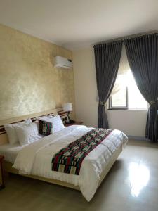 a bedroom with a large bed and a window at Axari Hotel & Suites in Calabar