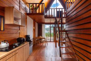 a kitchen with wooden walls and a staircase in a house at Cabin Linggayoni dieng in Diyeng