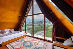 a room with a large window with a bed and a rug at Cabin Linggayoni dieng in Diyeng