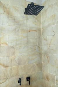 a bathroom with a shower with a stone wall at Cabin Linggayoni dieng in Diyeng +19 photos