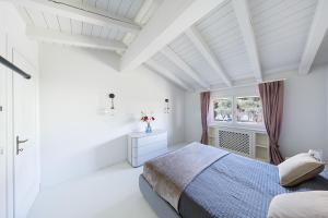 a white bedroom with a bed and a window at Bellavista by Whale Homes in Padenghe sul Garda