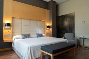 a bedroom with a large white bed and a chair at Los Claustros de Ayllón in Ayllón +57 photos