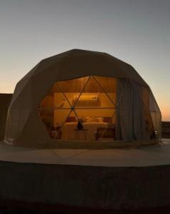 a dome tent with a person inside of it at Aman dome desert in Ḩawīyah +24 photos