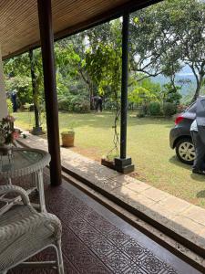 a porch with a table and a car in a park at Kandy summerhill bungalow in Kandy