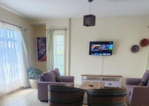 a living room with two couches and a tv on the wall at Swara Homes Nanyuki in Nanyuki +26 photos