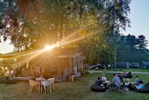 a group of people sitting in the grass under a tree at Natur Camp Birštonas in Birštonas