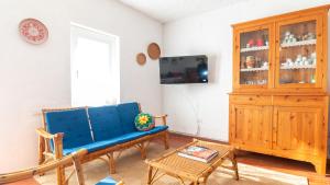 a living room with a blue couch and a wooden cabinet at S'Archittu Sunset House in S'archittu Cuglieri