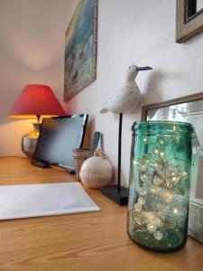 a desk with a vase filled with shells and a lamp at Le toit de Veules - Proche Mer - Veules les Roses in Veules-les-Roses