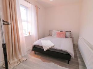 a bedroom with a bed with pink pillows and a window at San Antonio in Dungloe