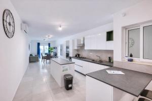 a kitchen with white cabinets and a large clock on the wall at Modern 3-bedroom apartment Pieta in Tal-Pietà