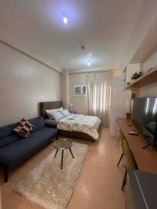 a living room with a blue couch and a bed at Sunvida Tower - Cebu Stay Rental in Dita