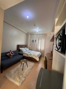 a living room with a blue couch and a bed at Sunvida Tower - Cebu Stay Rental in Dita