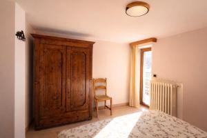 a bedroom with a wooden cabinet and a chair at Appartamento Alta Valle Maira - Provenzale in Villaro +7 photos