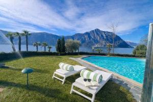 a backyard with a swimming pool and two chairs at Charming Suite am Luganersee, Pool, Parkplatz in Bissone
