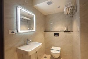 a bathroom with a sink and a toilet and a mirror at KG Residency Inn in Thanjāvūr