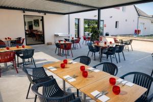 a patio with wooden tables and chairs and tables and tablesearcher at Logis Hôtel Angers Sud in Angers