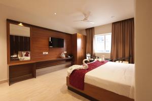 a hotel room with a bed and a television at KG Residency Inn in Thanjāvūr