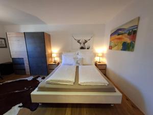 a bedroom with a bed with two lamps and a cow head on the wall at Haus Miriam in Mieming