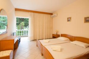 a hotel room with two beds and a balcony at Villa Alissia in Koukounaries