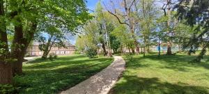 a path in a park with trees and a building at Le Clos du Bohon, 90m2 , calme dans l'Oise ,15 mn de Gisors et son chateau in Labosse