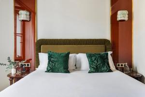 a large white bed with green pillows at Hôtel La Cour du 6 in Annecy