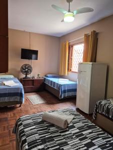 a room with two beds and a refrigerator in it at CASA 230 - Guest House in Piracicaba