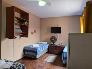 a bedroom with two beds and a tv in it at CASA 230 - Guest House in Piracicaba