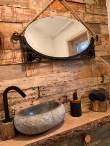 a bathroom sink with a mirror on a wooden wall at Chalet La Bohème in Prouilly